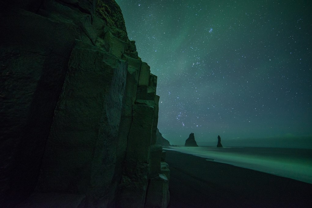 Aurora sobrevolando la playa de arena negra en Vik, Islandia
