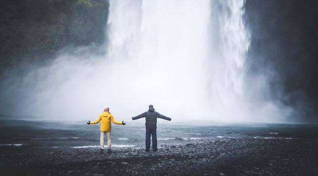 Couple Spreading Arms at Base of Waterfall