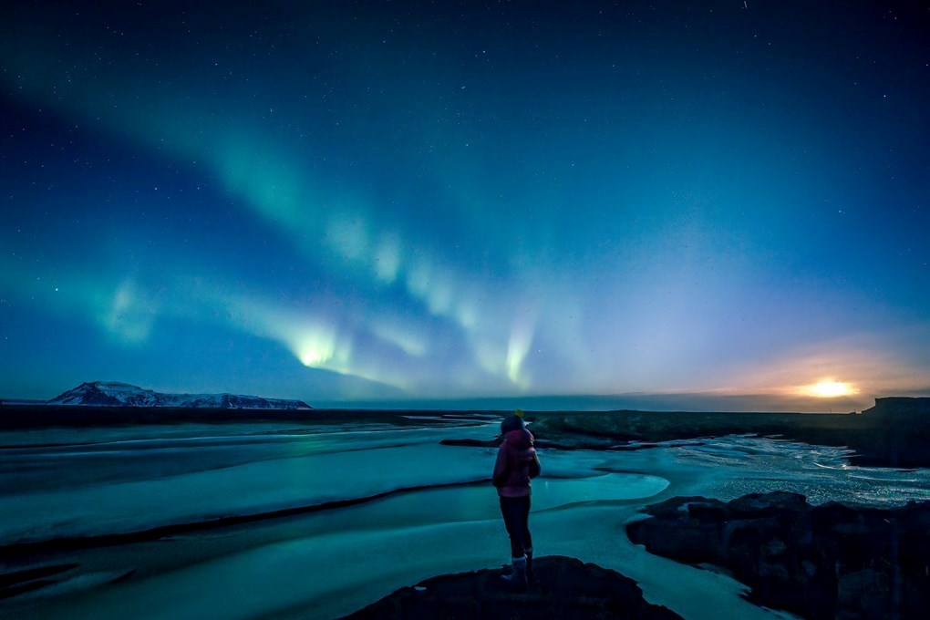 Person looking at northern lights in Iceland Person looking at northern lights in Iceland